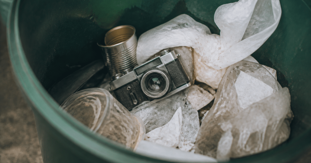 Appareil photo ancien posé dans poubelle plastique verte