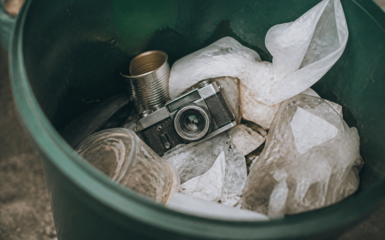 Appareil photo ancien posé dans poubelle plastique verte