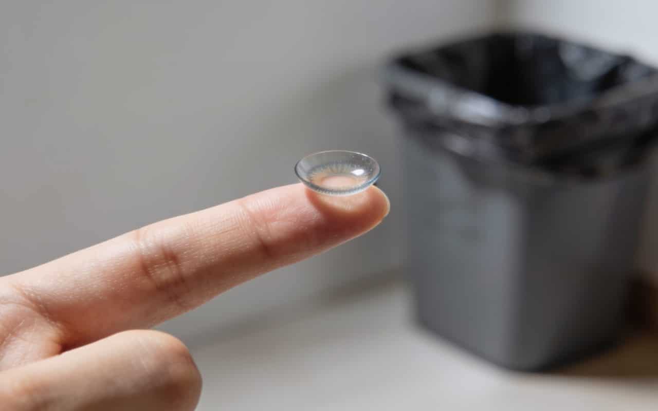 Lentilles de contact posees sur doigt tendu vers poubelle