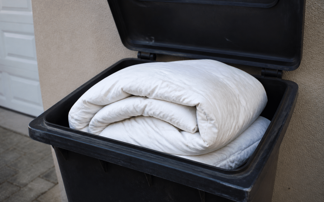 Edredon plié posé dans un bac de recyclage ouvert.