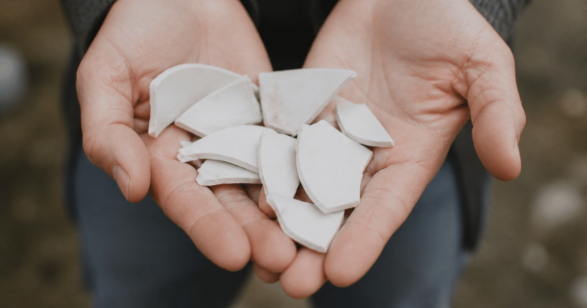 Mains tenant des fragments de porcelaine blanche cassee