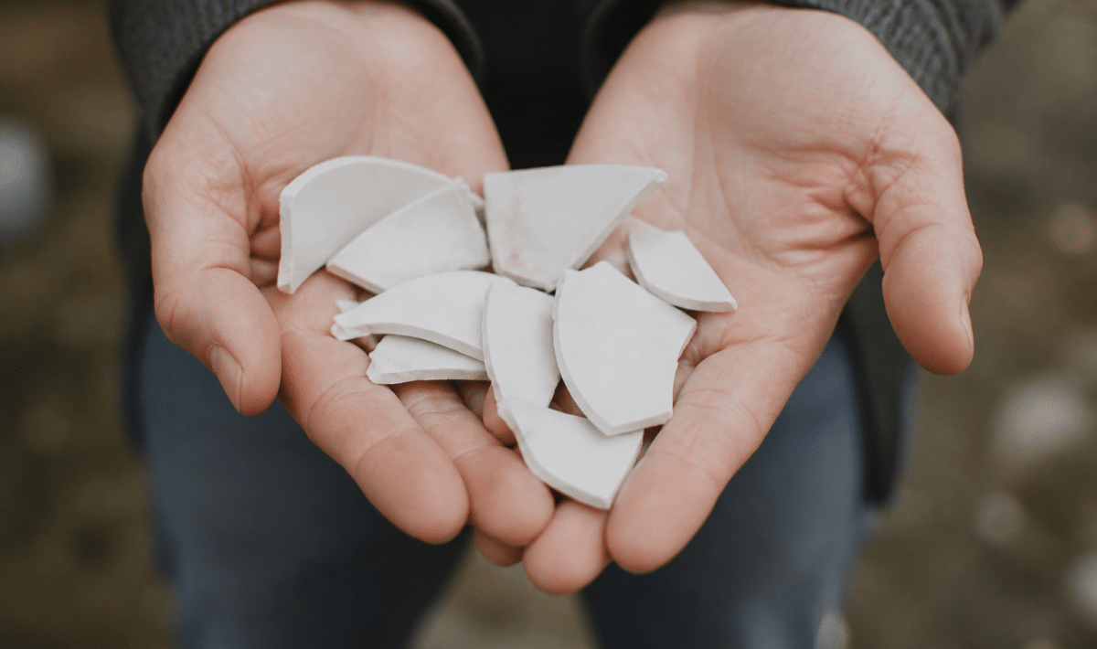 Mains tenant des fragments de porcelaine blanche cassee