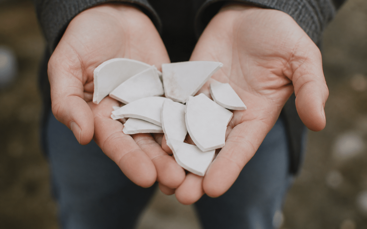 Mains tenant des fragments de porcelaine blanche cassee