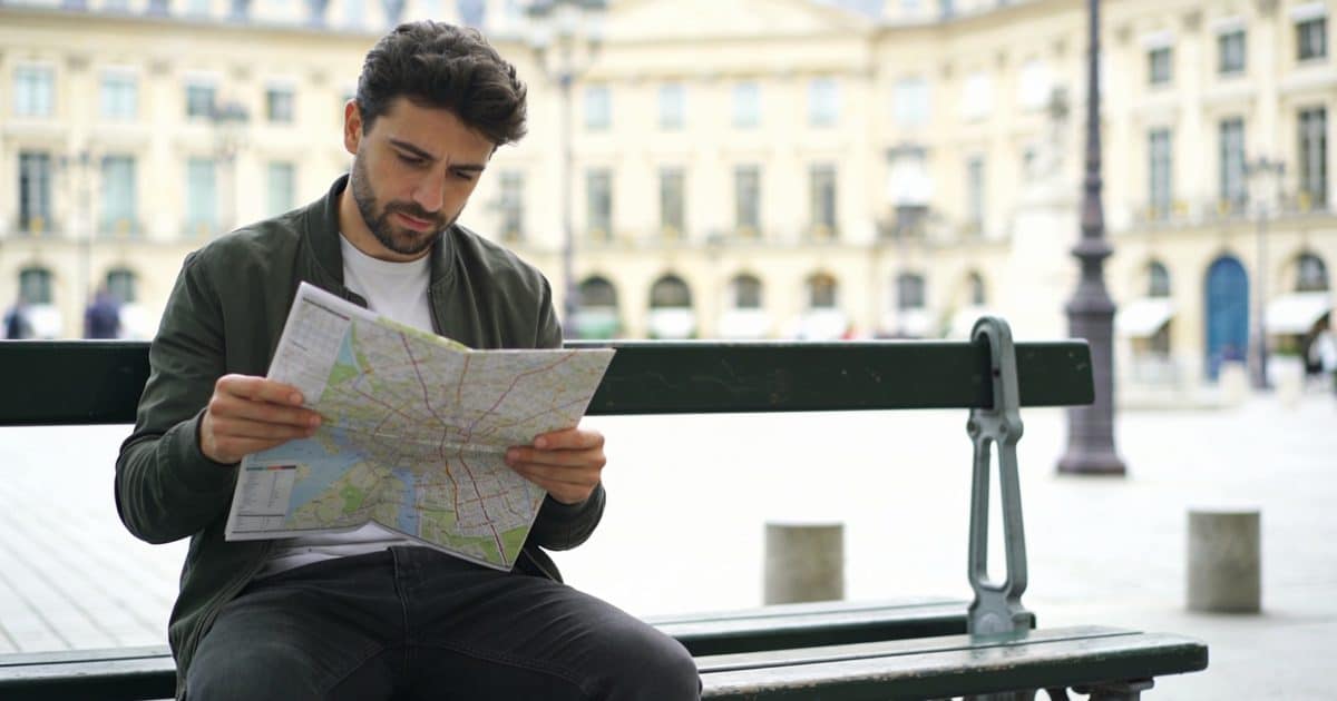 Homme regardant une carte sur un banc parisien