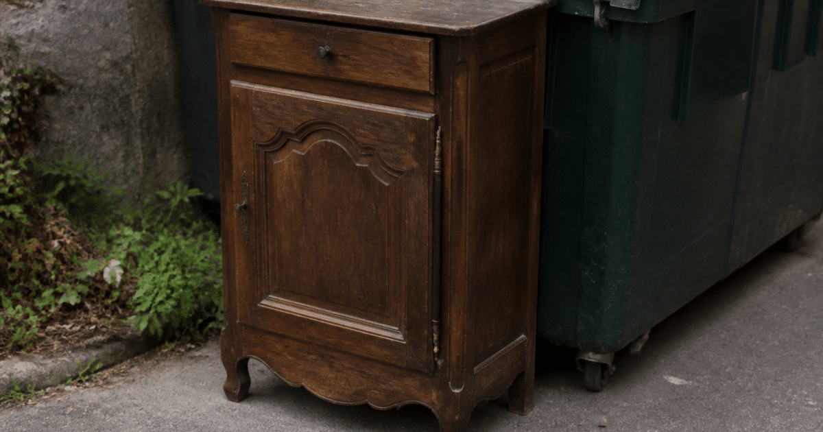 Meuble ancien depote pres d'une benne de recyclage.