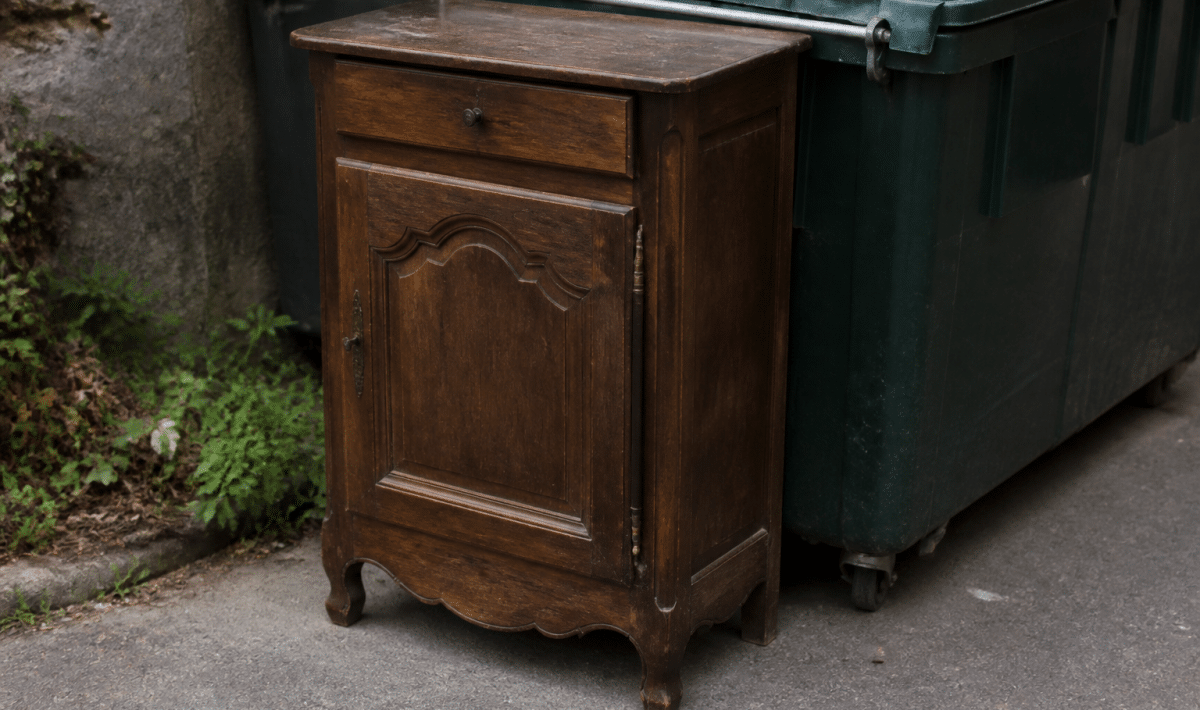 Meuble ancien depote pres d'une benne de recyclage.