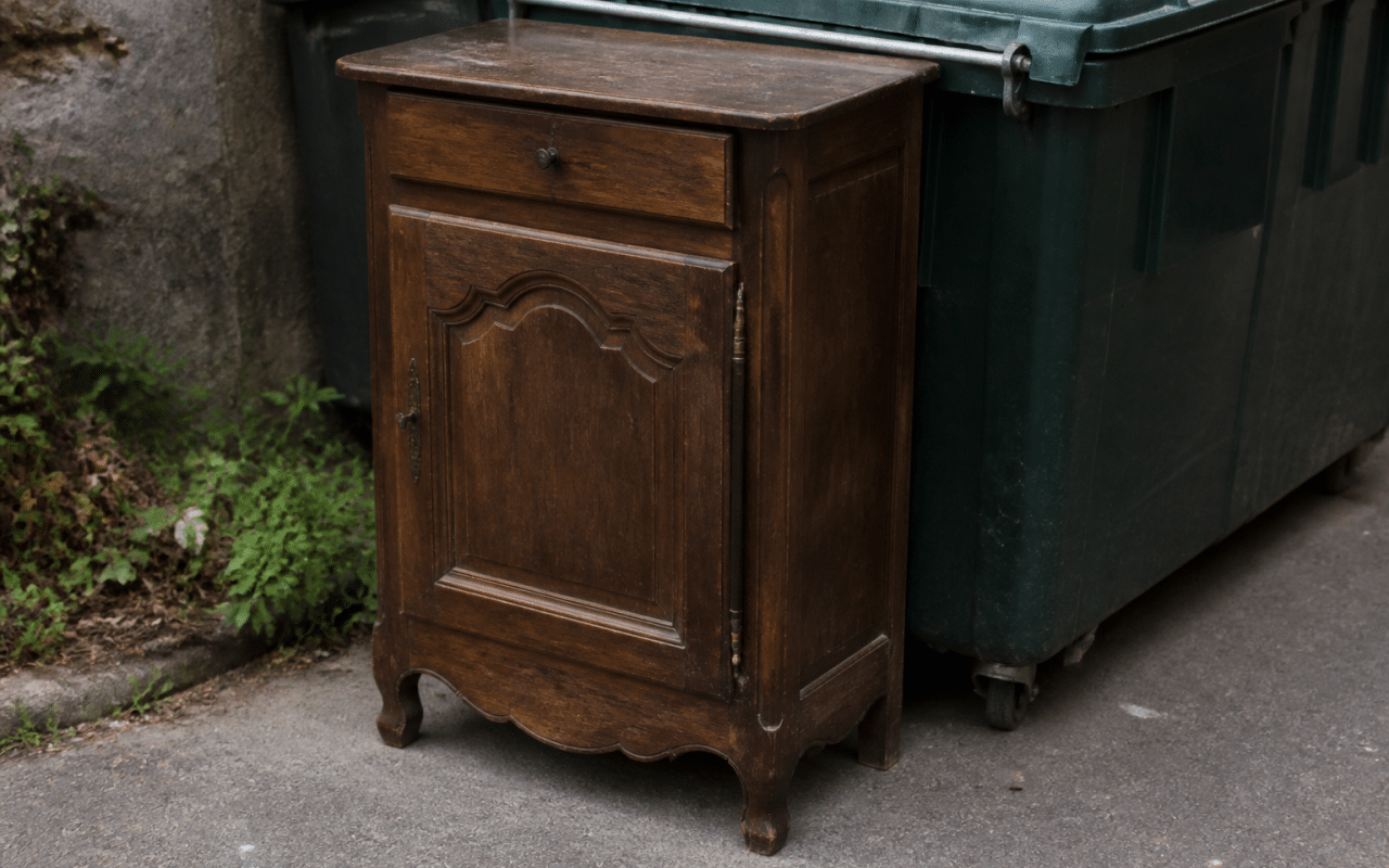 Meuble ancien depote pres d'une benne de recyclage.