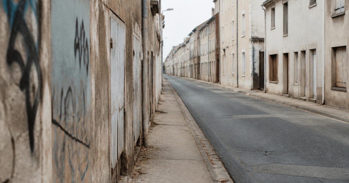 Rue vide de Montluçon avec immeubles délabres et graffitis.