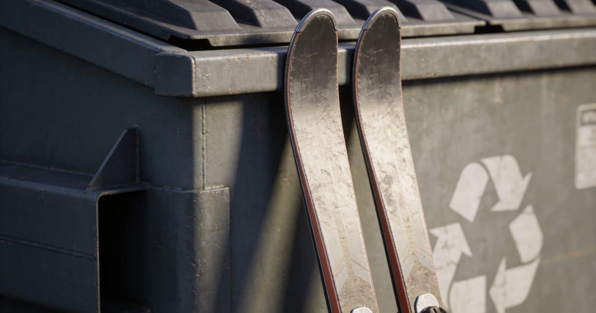 Paire de skis appuyees contre container recyclage exterieur