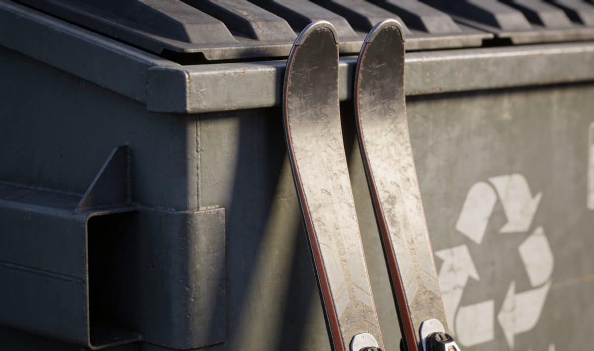 Paire de skis appuyees contre container recyclage exterieur