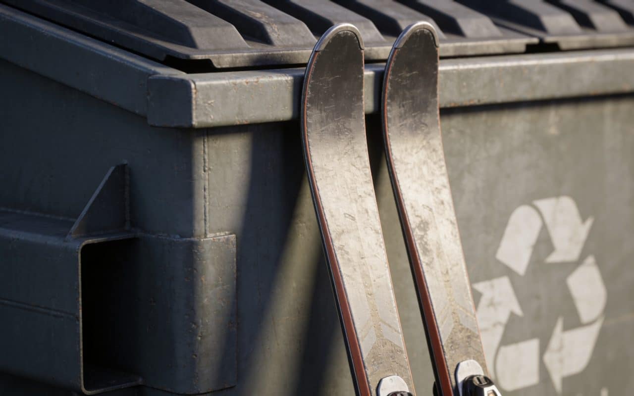 Paire de skis appuyees contre container recyclage exterieur