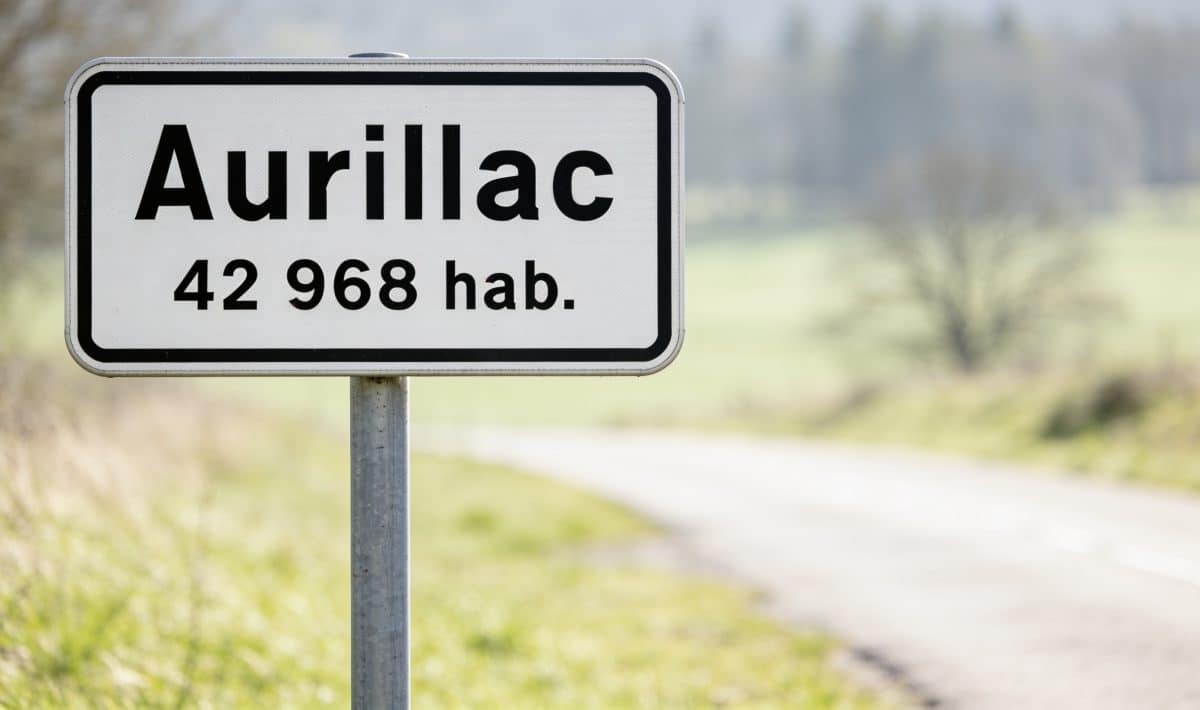 Panneau routier affichant le nom Aurillac avec chiffres population