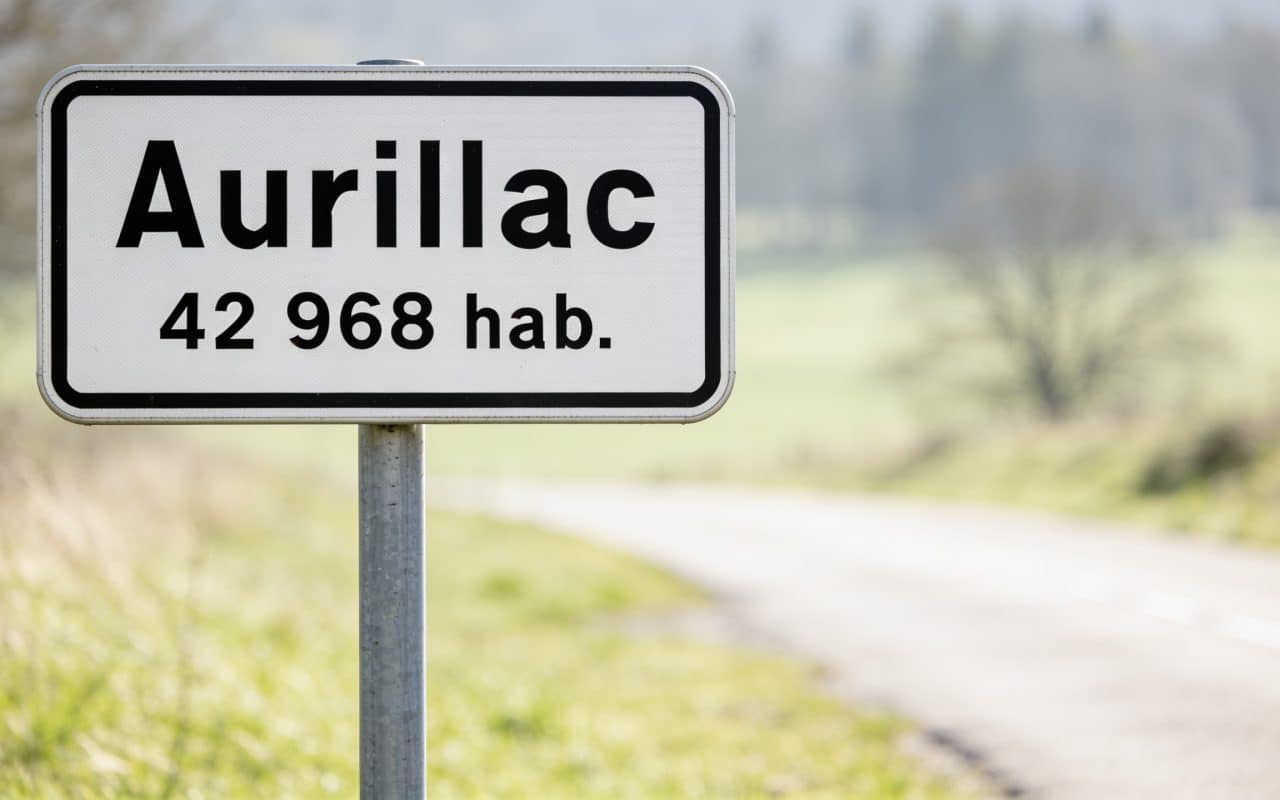 Panneau routier affichant le nom Aurillac avec chiffres population