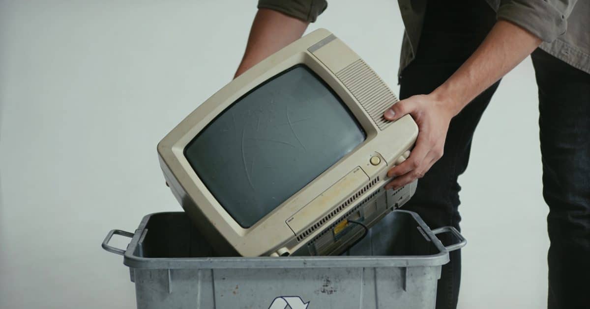 Personne deposant un vieux televiseur dans un conteneur de recyclage