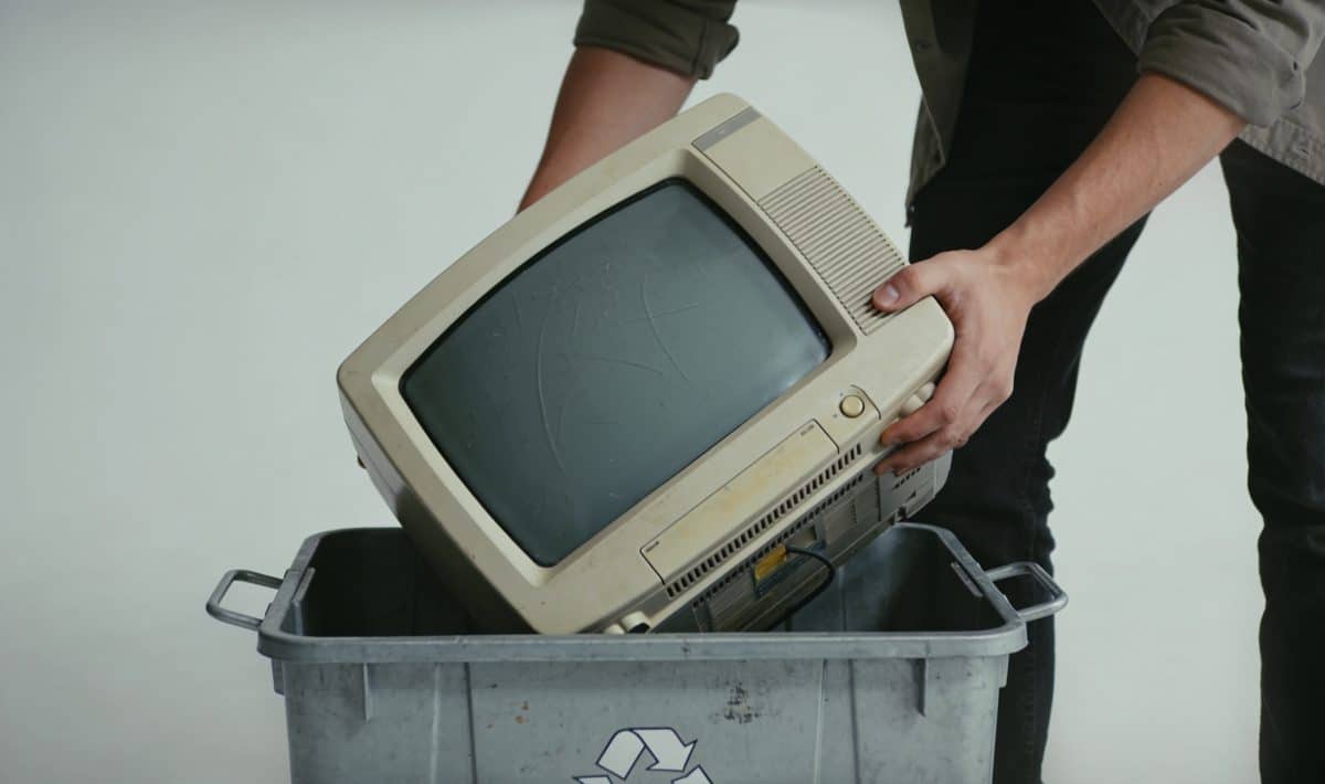 Personne deposant un vieux televiseur dans un conteneur de recyclage