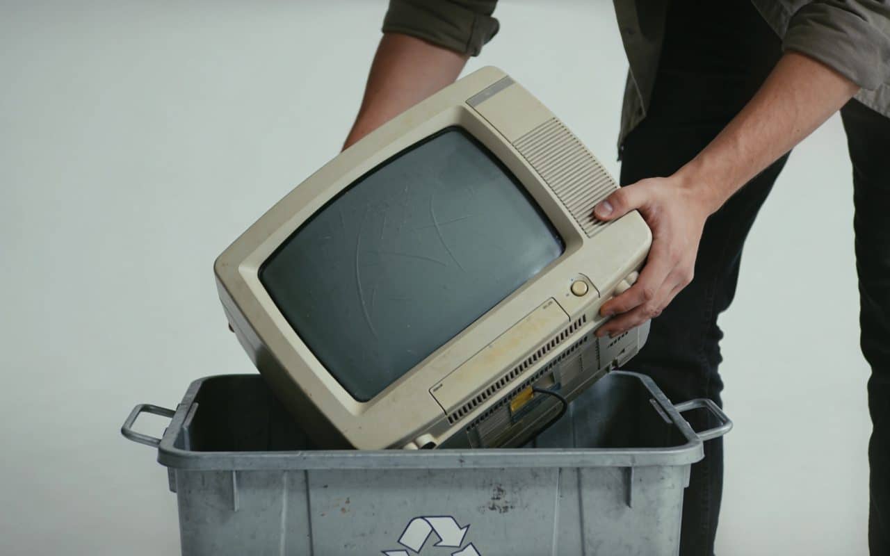 Personne deposant un vieux televiseur dans un conteneur de recyclage