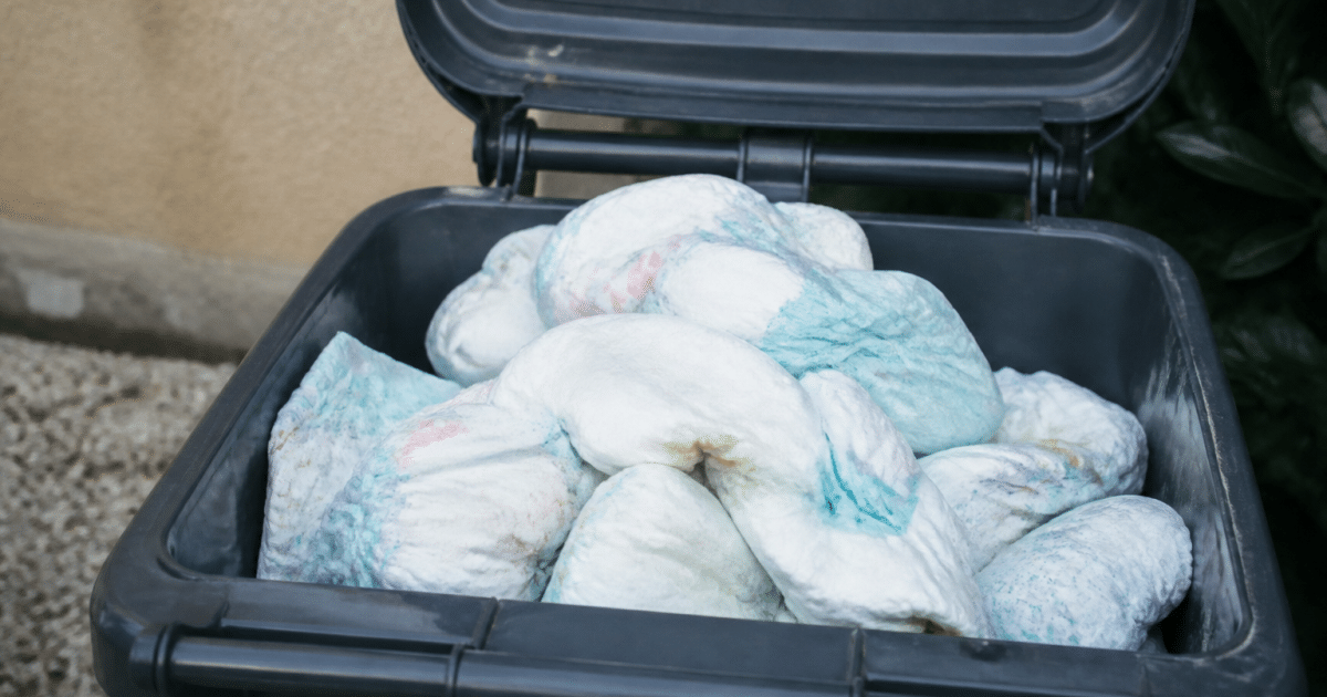 Pile de couches usees dans bac poubelle exterieur