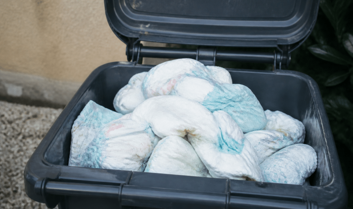 Pile de couches usees dans bac poubelle exterieur