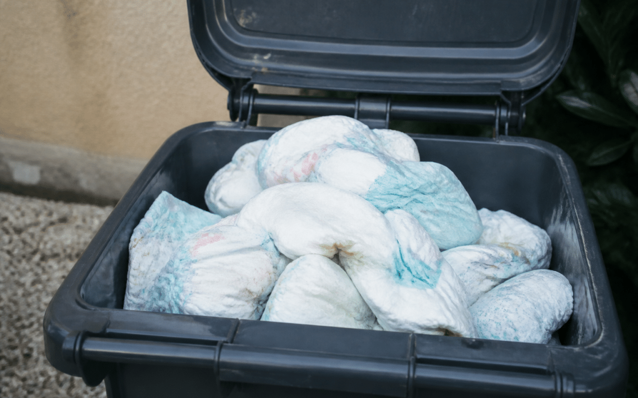 Pile de couches usees dans bac poubelle exterieur