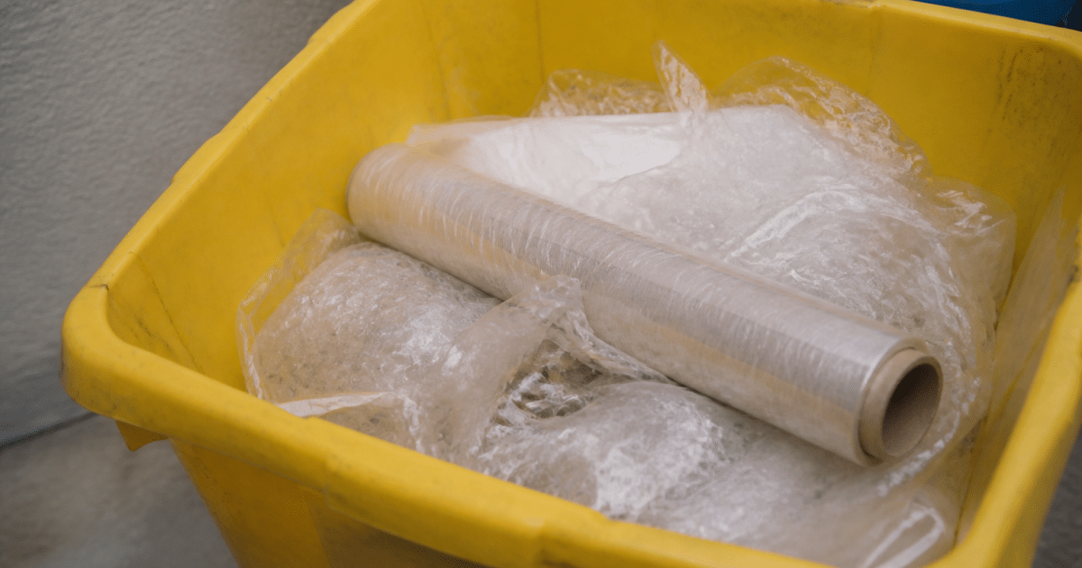 Rouleau de film plastique transparent jeté dans bac recyclage.