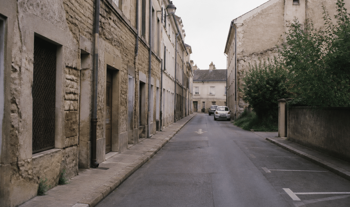 Rue déserte de Dijon avec immeubles dégradés et façades endommagées