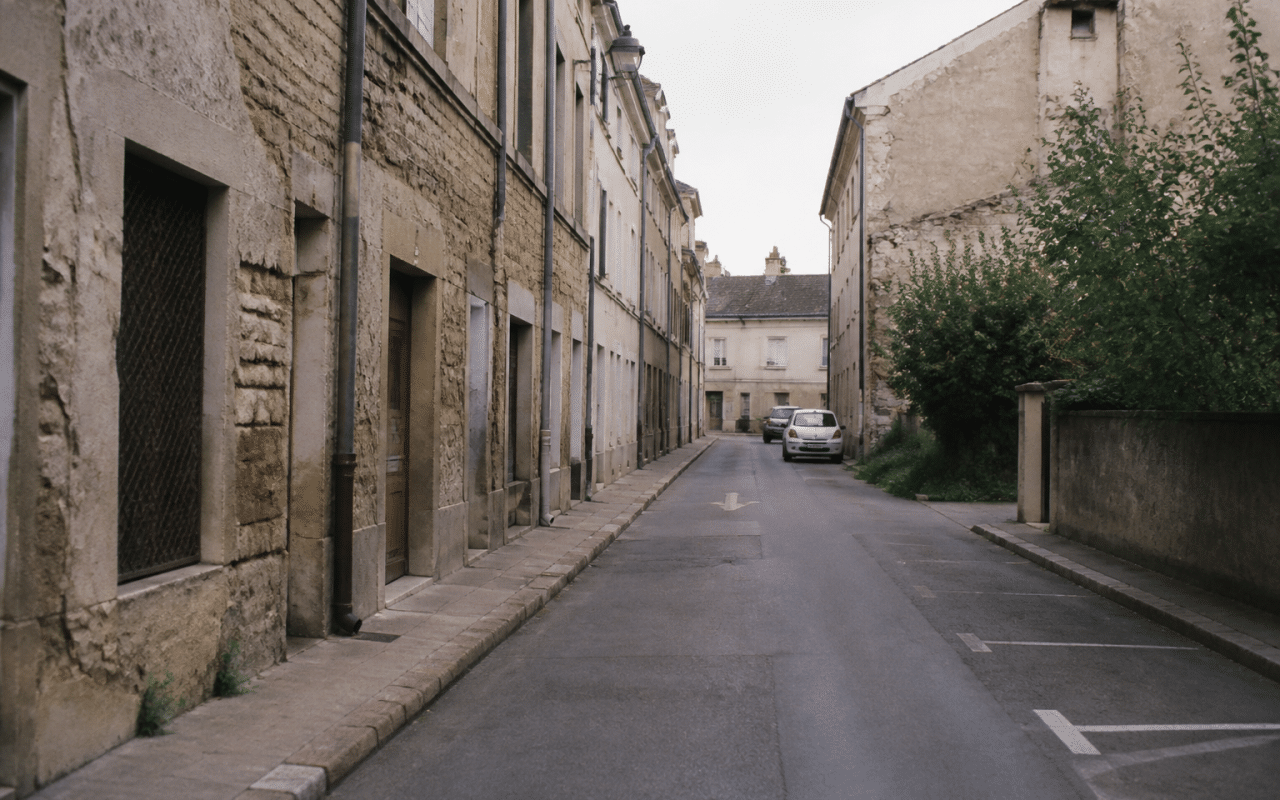 Rue déserte de Dijon avec immeubles dégradés et façades endommagées