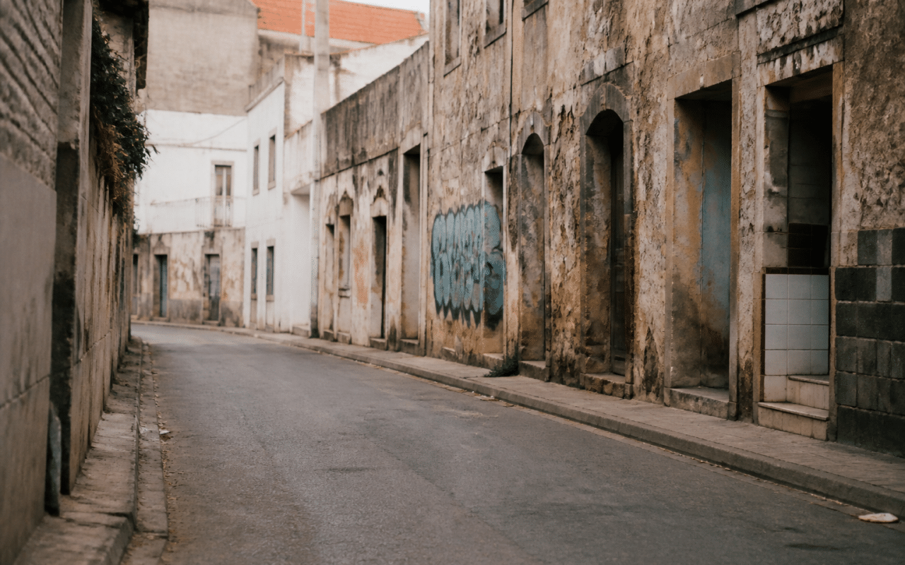 Rue urbaine déserte avec immeubles délabidés et graffitis visibles
