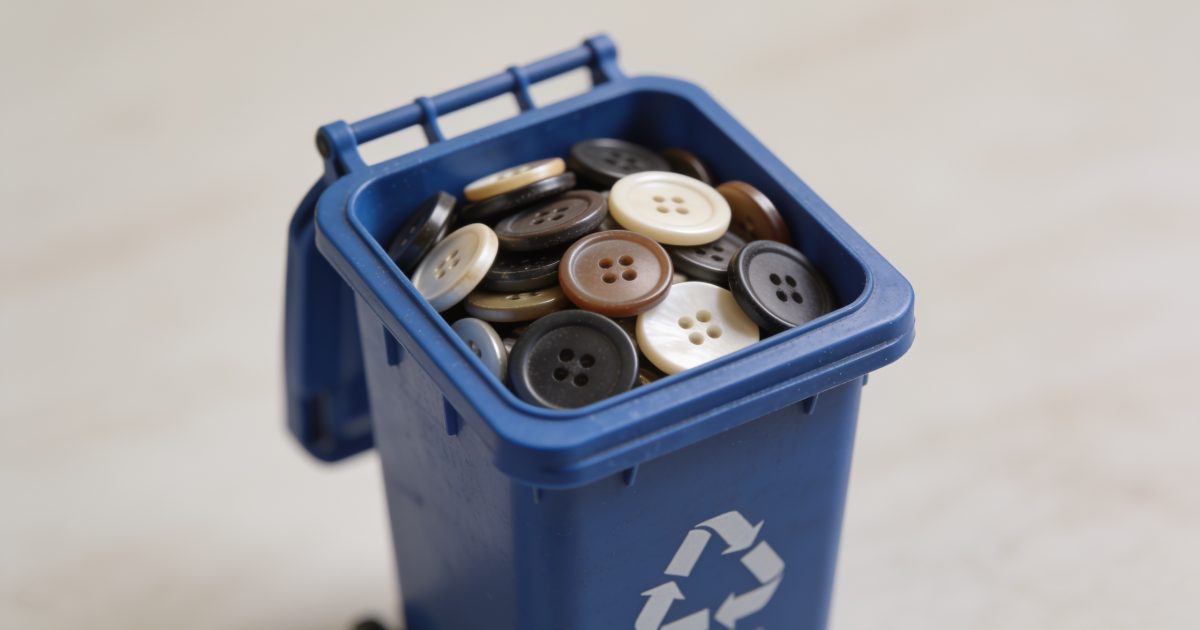 Petite pile bouton placee dans bac recyclage bleu.